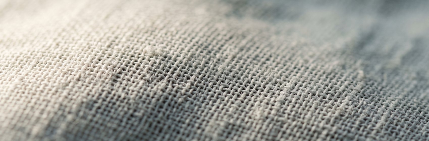 Extreme close-up of fine cotton muslin, the weave lit by raking side light
